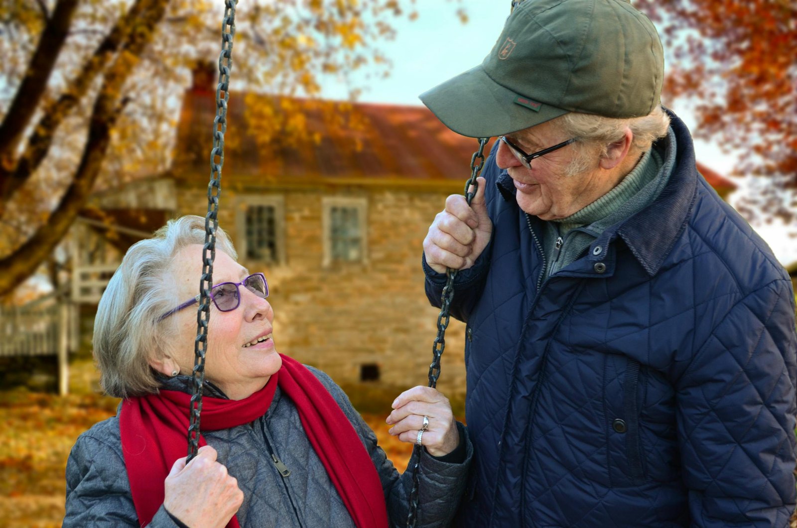 Un couple de personne âgées partage un joyeux moment sur une balançoire devant leur maison qu’ils ont vendue en viager sur deux têtes.