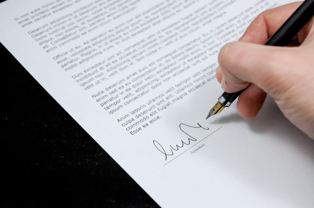 Focus sur une main signant un document juridique lié au viager avec un stylo plume
