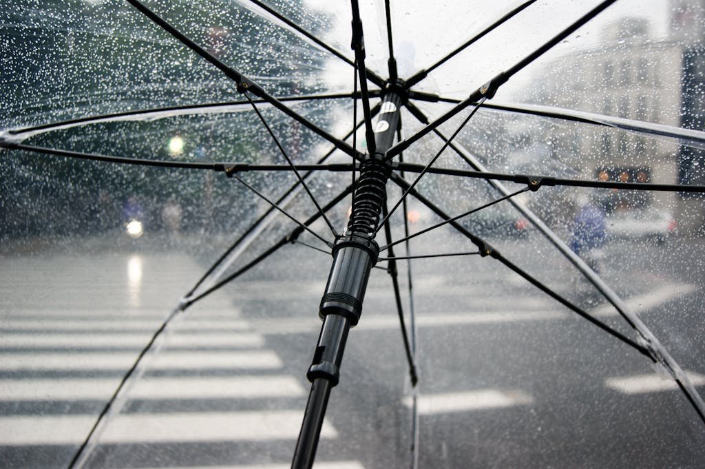 Un parapluie transparent ouvert dans une rue pluvieuse qui sympbolise les garanties d’un vente en viager pour protéger le crédirentier contre les impayés.