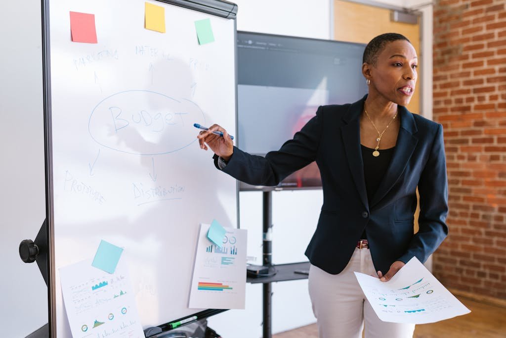 Femme d’affaires qui explique des stratégies patrimoniales liées au viager sur un tableau blanc pendant une réunion.
